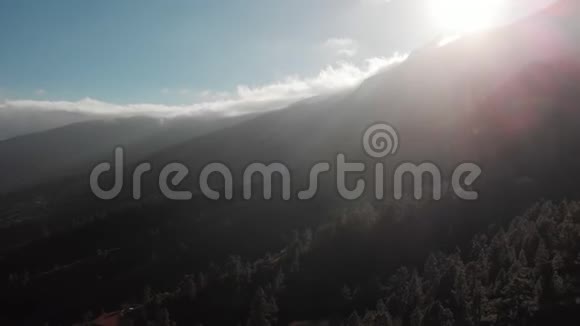 空中射击摄像机向后移动在山上日落的时候在一片深绿色树林的背景下视频的预览图