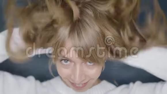 快乐的微笑女孩与美丽的金发卷发摆在美容工作室视频的预览图