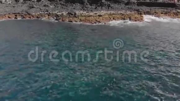 空中射击蓝色和绿松石的海洋泡沫波火山岸是山滩的纹理表面视频的预览图