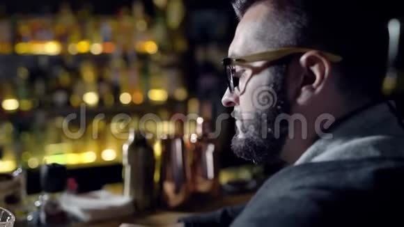 一个成年人独自喝啤酒晚上坐在酒吧里品尝鸡尾酒在柜台上旋转玻璃杯视频的预览图