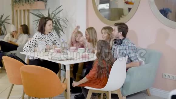 快乐的成年女人男人和小孩坐在舒适的咖啡馆里白天喝热巧克力视频的预览图
