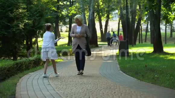 快乐的女孩在公园里给奶奶讲故事信任亲戚视频的预览图
