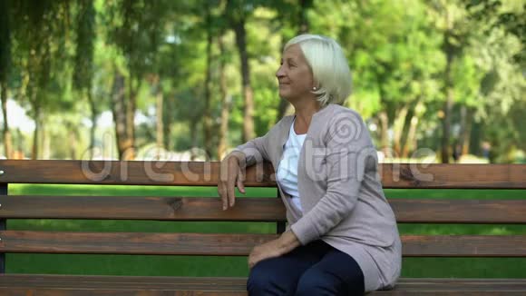自信的成熟女人在公园的长椅上休息享受周末快乐视频的预览图