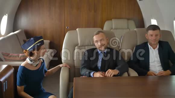 三个商务人士在私人飞机内放松并与空姐交谈视频的预览图