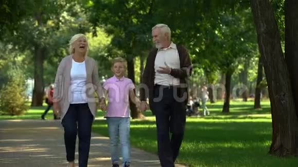 小男孩和爷爷奶奶在公园散步周末旅游一起度过快乐时光视频的预览图
