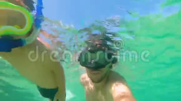 4k水下射击一个可爱的小男孩和他的父亲带着面具和管子在热带海洋里浮潜视频的预览图