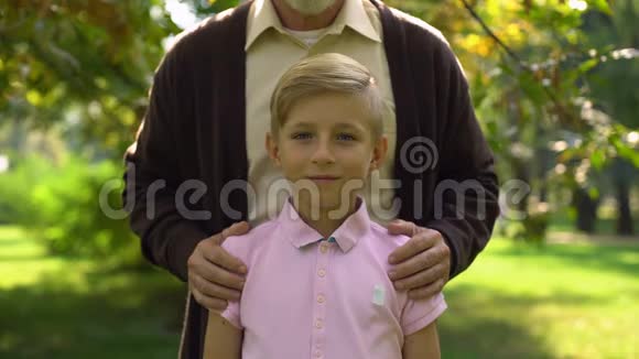 男性养老金领取者拥抱男孩摆姿势拍照家庭支持有保障的童年视频的预览图
