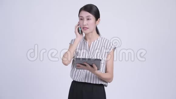 忙碌的亚洲女商人用电话和数码平板电脑聊天视频的预览图