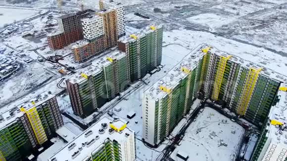 冬季日落时在雪域背景下俯瞰城市动作鸟瞰绿色和黄色的高大视频的预览图