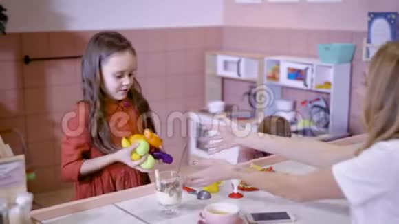 可爱的小女孩正给妈妈带着人造玩具水果坐在柜台前的灯光下孩子们都是视频的预览图