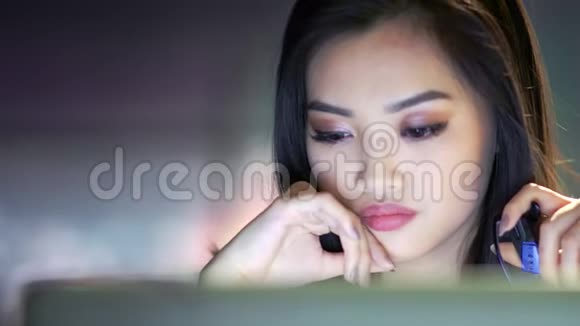 一位体贴的亚洲女性在办公室工作晚上看电脑屏幕视频的预览图