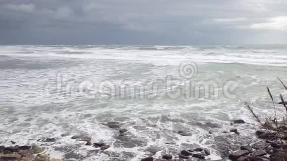 浅沙滩上的海浪翻滚着带着岩石视频的预览图