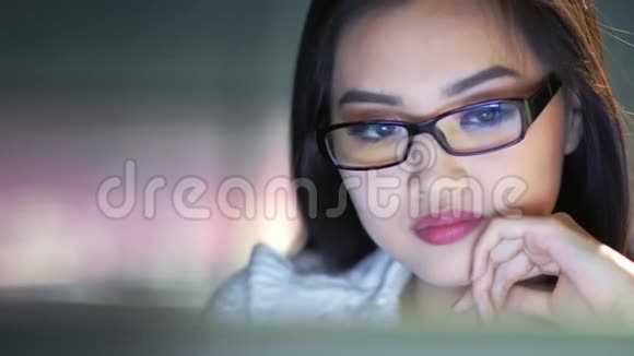 在深夜欣赏网上购物观看电脑屏幕的亚洲女商人视频的预览图