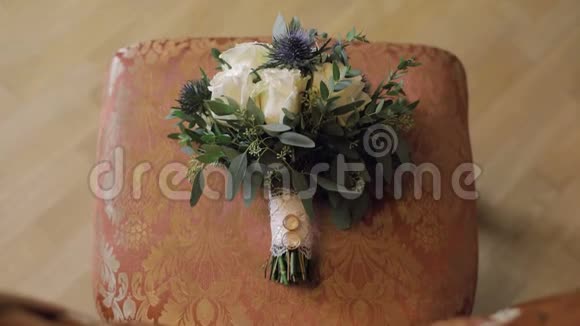结婚戒指放在一束漂亮的婚礼花束上放在椅子上视频的预览图