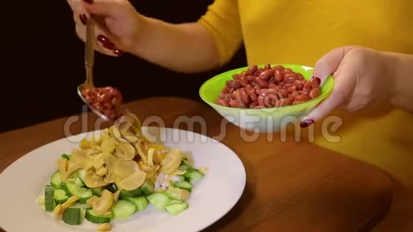 一个女人用勺子把红豆放进一盘沙拉里视频的预览图