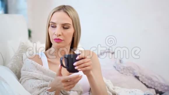 穿着暖和的格子布坐着喝热饮料的漂亮女人视频的预览图