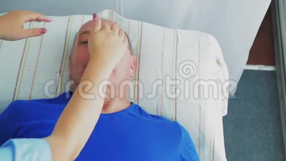 女性美容师在一家水疗沙龙里给男人一个坚定的面部按摩视频的预览图