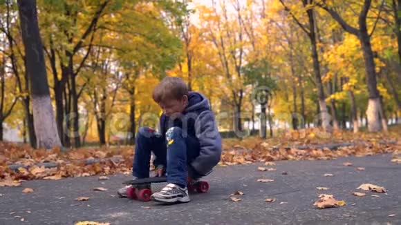 小男孩坐在滑板上滚动视频的预览图