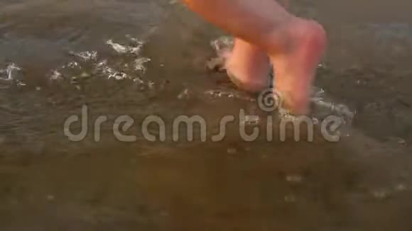 幼儿在沙滩上踩水快乐的孩子在水里踩脚特写慢动作视频的预览图