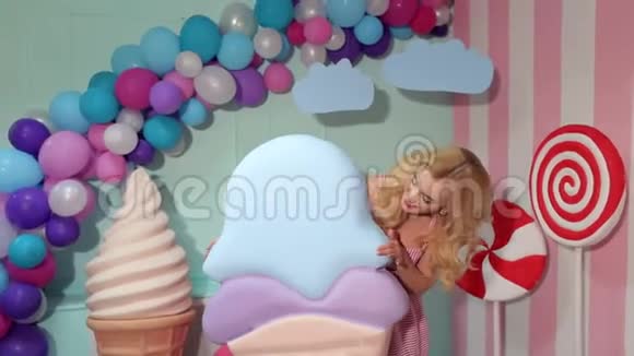 一个穿着粉红色裙子的迷人女孩正拿着一个巨大的五颜六色的冰淇淋糖果女孩视频的预览图