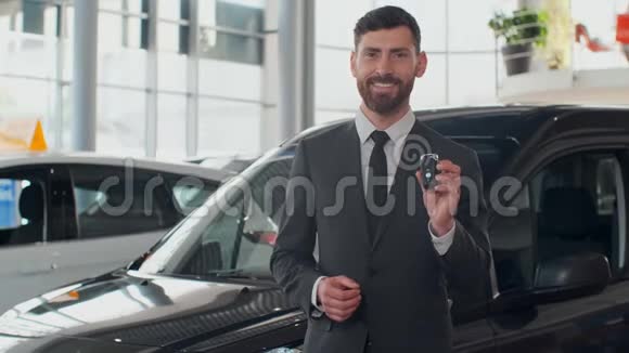专业的汽车推销员微笑着幸福地拿着车钥匙站在经销商的新车前面视频的预览图