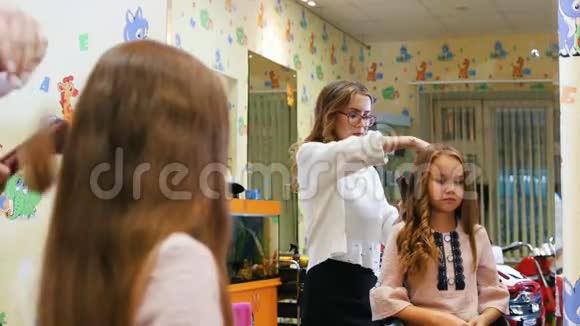 发型师用电卷发铁为小女孩卷发透过镜子视频的预览图