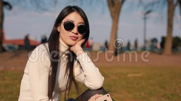 戴眼镜坐在公园里的亚洲女人视频的预览图