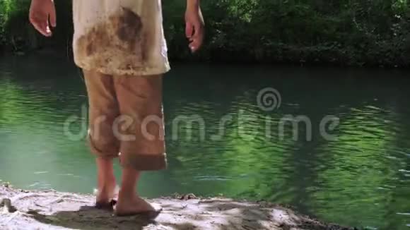 两个穿着脏衣服光着脚在河岸上游荡的男孩视频的预览图
