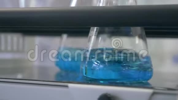 在实验室玻璃器皿中混合液体在实验室玻璃器皿中混合蓝色液体实验室烧瓶混合视频的预览图