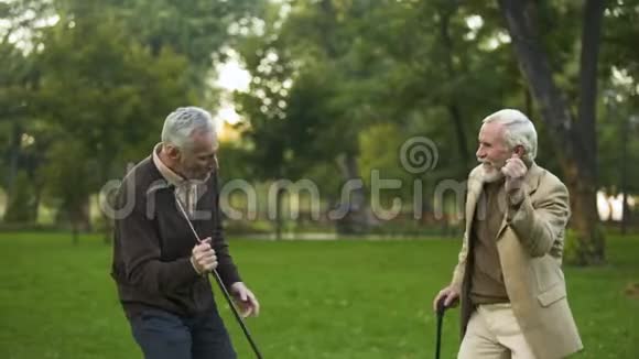男性退休者用手杖在公园跳舞友谊幽默玩得开心视频的预览图