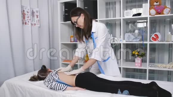 女医生在诊所里给小女孩的背部按摩视频的预览图