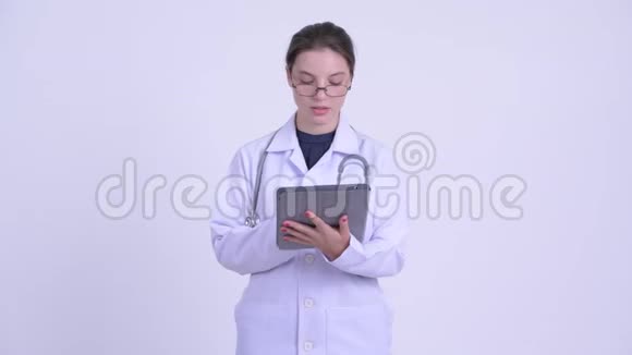 快乐年轻美丽的女医生用数码平板电脑思考视频的预览图