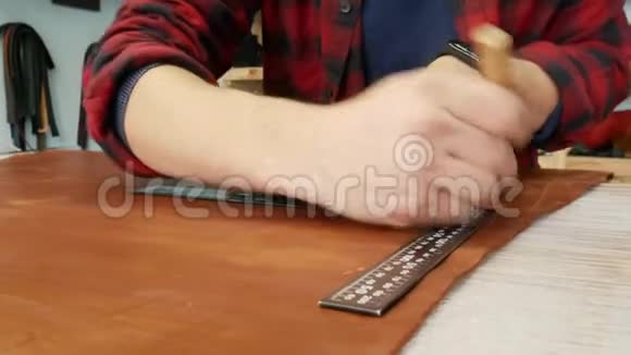 年轻的工匠用尺子在皮布上做一行标记手工皮革制品视频的预览图