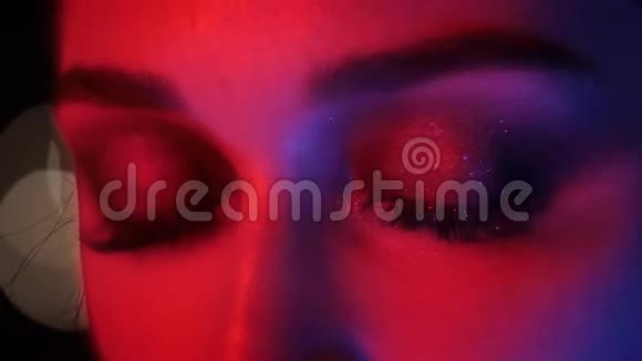 特写镜头漂亮的女性眼睛与惊人的时尚化妆与红色霓虹灯和波克背景在夜总会视频的预览图