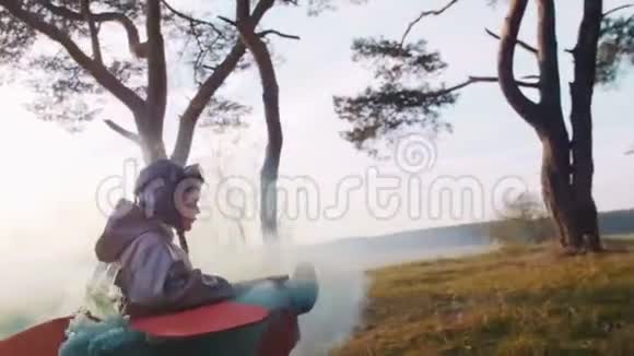 镜头跟随小快乐飞行员男孩跑在森林穿着纸板飞机服装与彩色烟雾慢动作视频的预览图