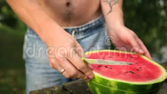 年轻人把刀切成片大的熟红西瓜在大街上阳光明媚视频的预览图