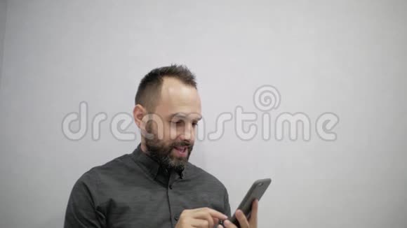 一个穿着衬衫和胡子的男人在电话里写短信视频的预览图