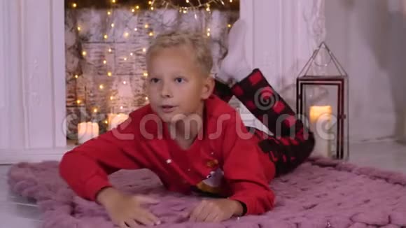 男孩少年躺在地毯背景装饰圣诞壁炉视频的预览图