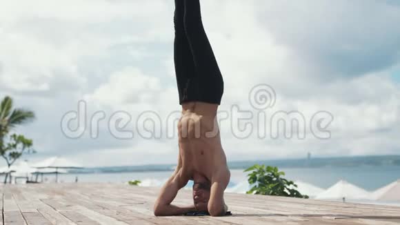 在美丽的海滩上用倒立做瑜伽运动的人视频的预览图