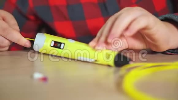 少年男孩在3D笔中插入一块黄色ABS塑料他创造了一个塑料三维图形视频的预览图