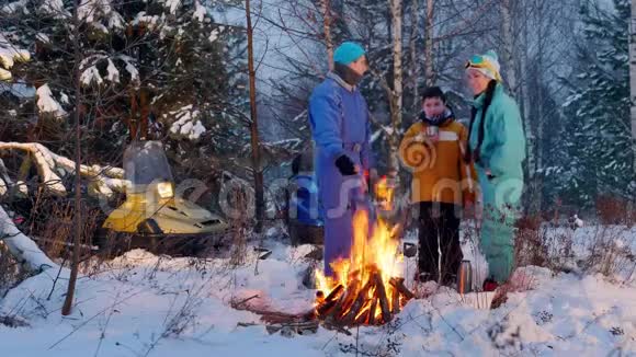 冬季森林露营一家人站在火边的树林里拍自拍视频的预览图