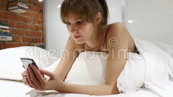 躺在床上的放松的女人趴在肚子上打电话视频的预览图