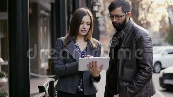 白人男人和女人站在街上手里拿着平板电脑说话看着什么视频的预览图