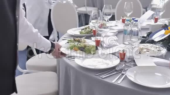 饮食服务服务员在婚礼或会议上把盘子和盘子放在客人的桌子上视频的预览图