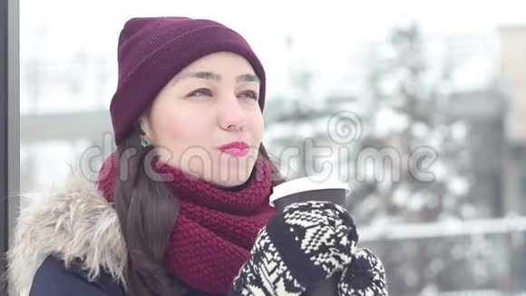 美丽的年轻女孩在一个冬天的公园里在一个浪漫的心情和乐趣喝咖啡通过稻草视频的预览图