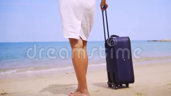 商务女性带着一个手提箱沿着美丽的大海的海岸散步女腿带着手提箱走在岸边视频的预览图