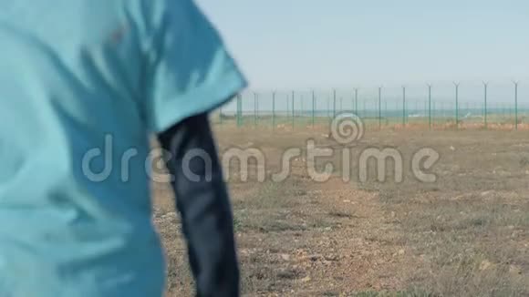 阳光明媚的一天一个快乐奔跑的小男孩在边境附近的沙漠中难民视频的预览图