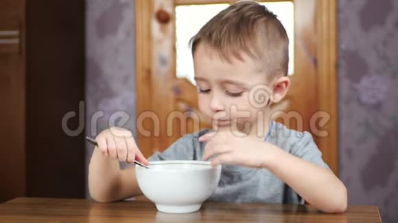 可爱的小男孩坐在桌子旁吃着有食欲的汤儿童的营养和健康视频的预览图