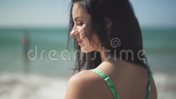 肖像美丽幸福的女孩站在大海的背景上年轻漂亮的女人长着深色的脸视频的预览图