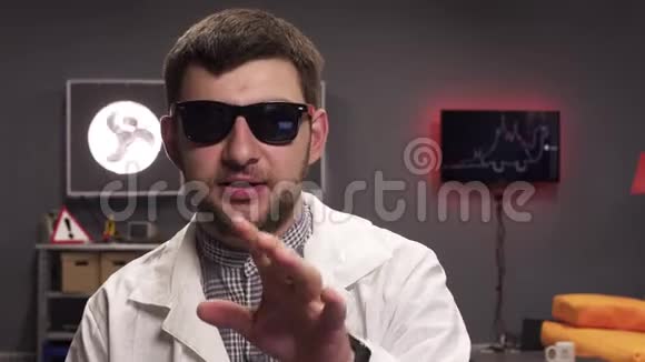 可爱的年轻男性戴着太阳镜和白色的实验室外套积极说话视频的预览图